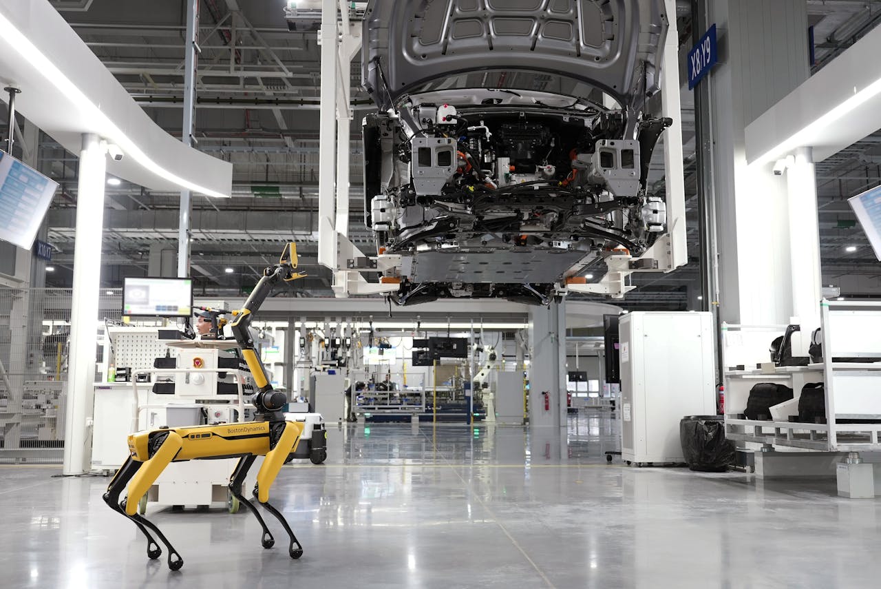 Services-02 A robotic dog oversees an automated car assembly in a high-tech factory setting.
