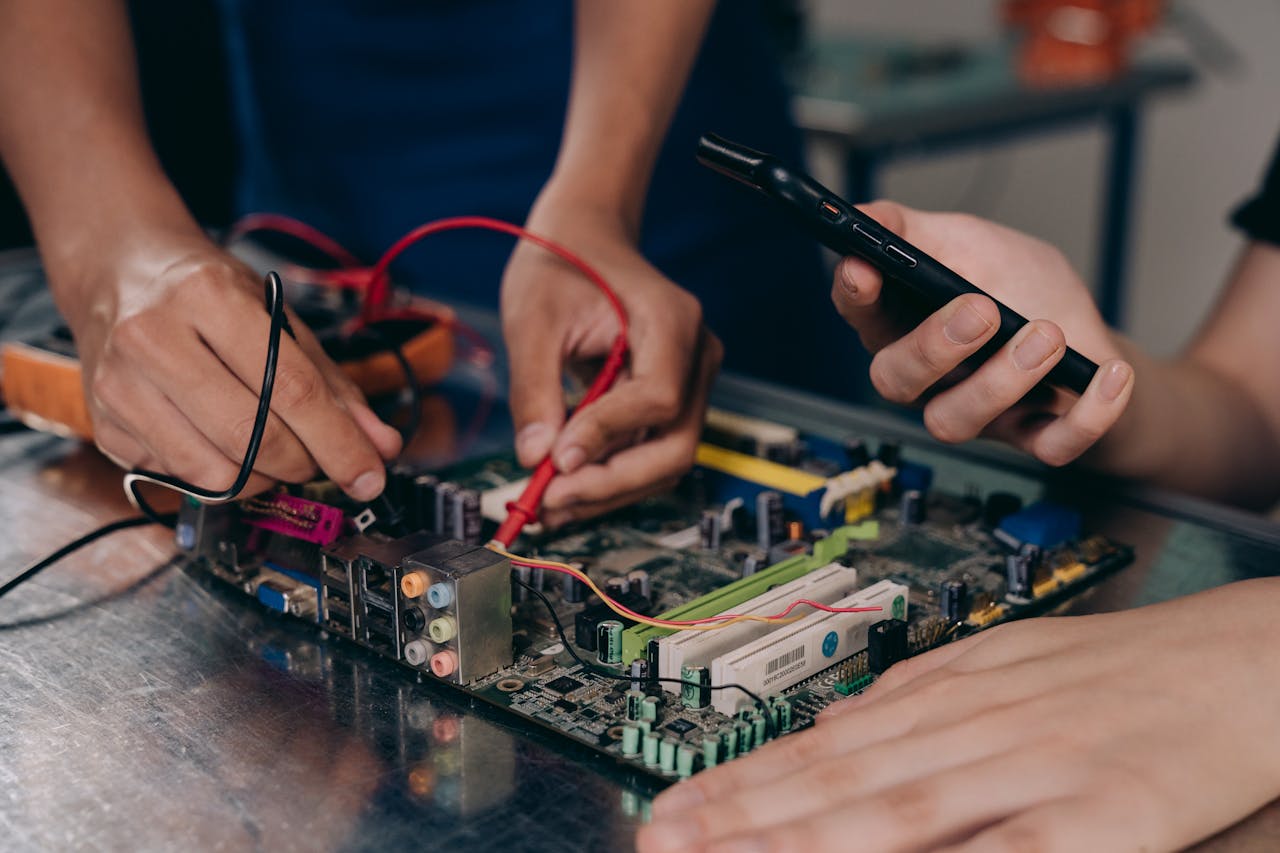 creative Close-up of hands working on a motherboard using electrical tools and tester.
